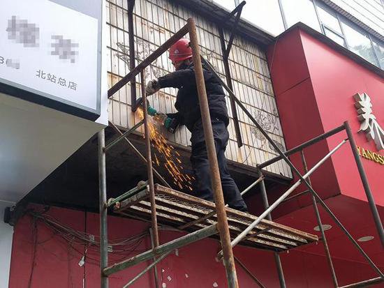 柳北城管清理沿街破损招牌，保障居民“头顶上的安全”